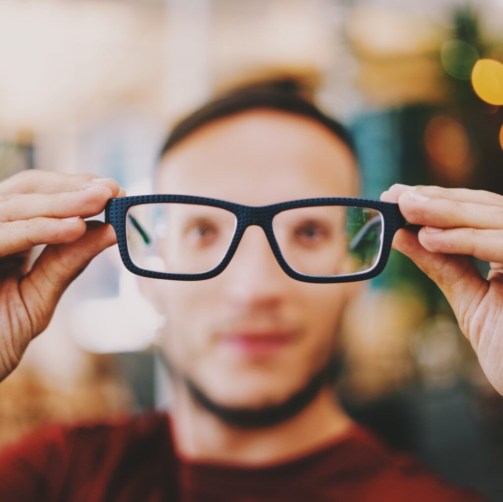 person holding eyeglasses with black frames