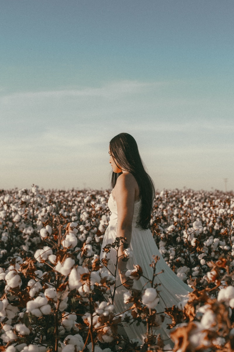 woman in white dress standing on flower field during daytime