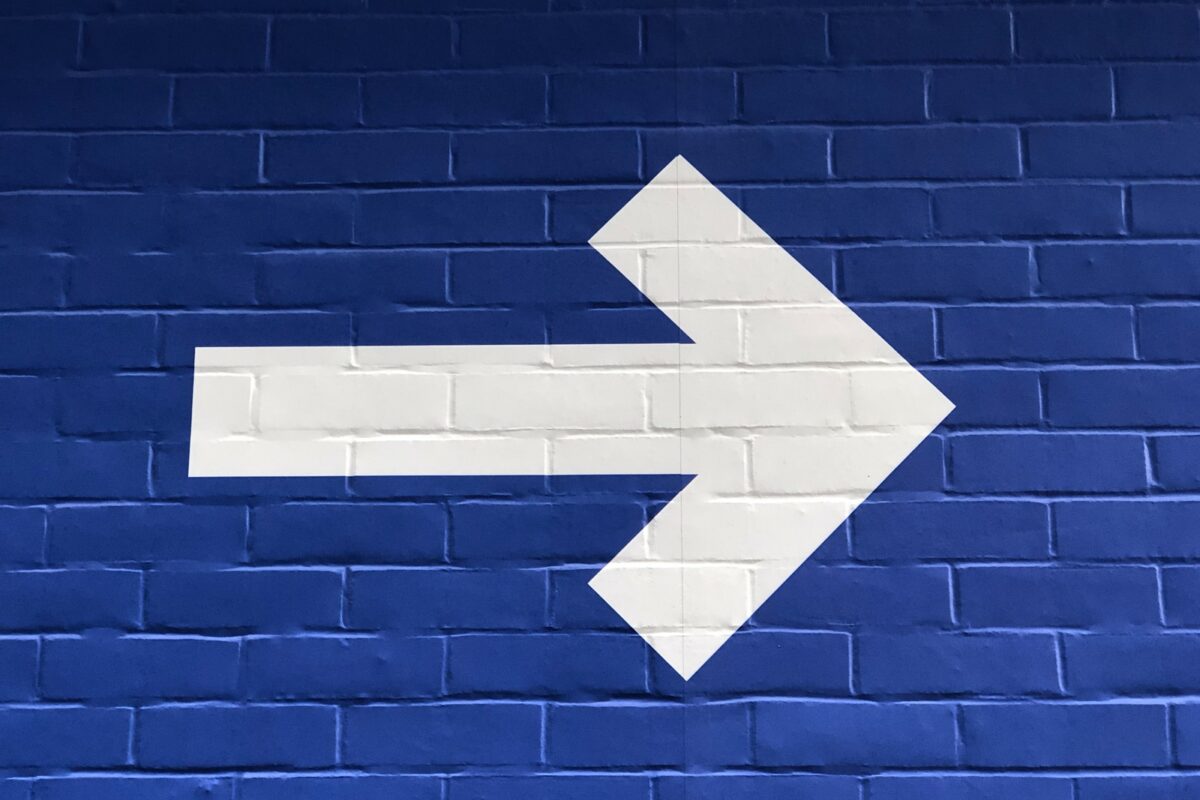 white arrow painted on brick wall