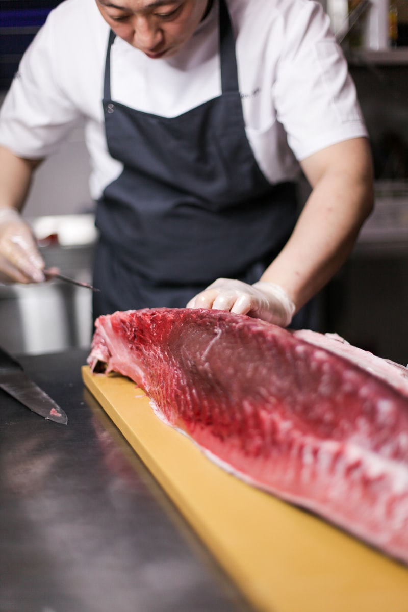 person cutting raw fish meat